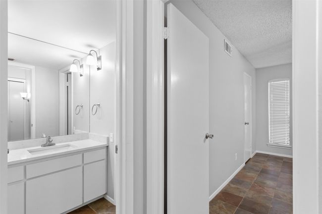 Bathroom with visible vents, vanity, baseboards, a textured ceiling, and stone finish flooring | Image 21