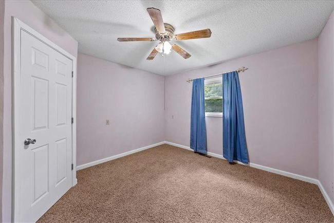 Empty room featuring baseboards, carpet flooring, ceiling fan, and a textured ceiling | Image 53