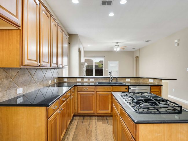 Kitchen featuring arched walkways, black gas stovetop, light wood-style floors, a ceiling fan, and recessed lighting | Image 15