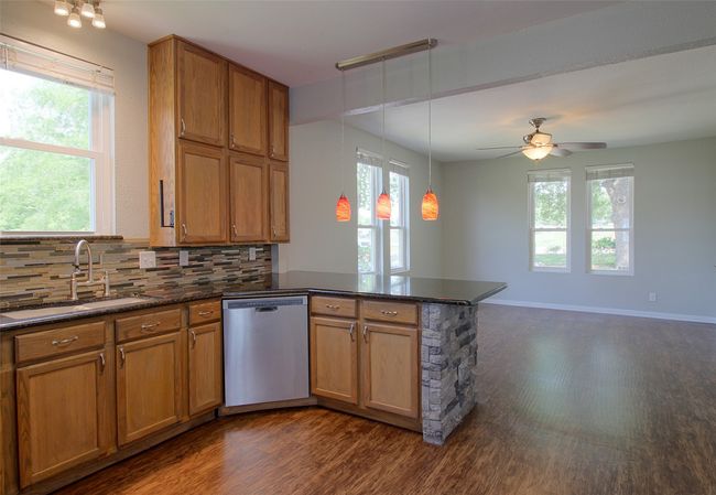 Kitchen featuring a sink, dishwasher, backsplash, a peninsula, and dark wood-type flooring | Image 9