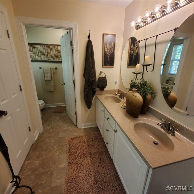 Bathroom with double vanity, toilet, baseboards, and a sink | Image 35