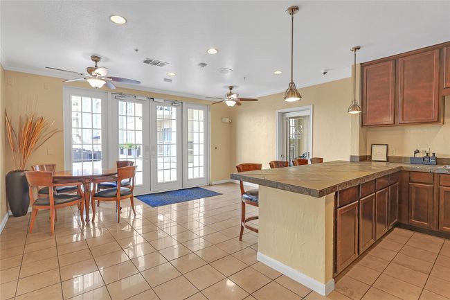 Kitchen with a peninsula, a kitchen bar, ornamental molding, pendant lighting, and light tile patterned floors | Image 23