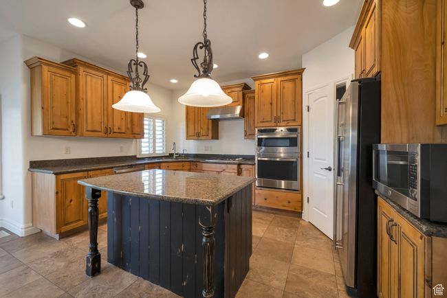 Kitchen featuring a sink, stainless steel appliances, brown cabinetry, and under cabinet range hood | Image 9
