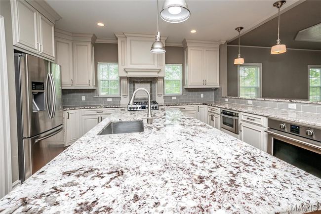 Kitchen with pendant lighting, tasteful backsplash, a sink, stainless steel appliances, and light stone countertops | Image 14