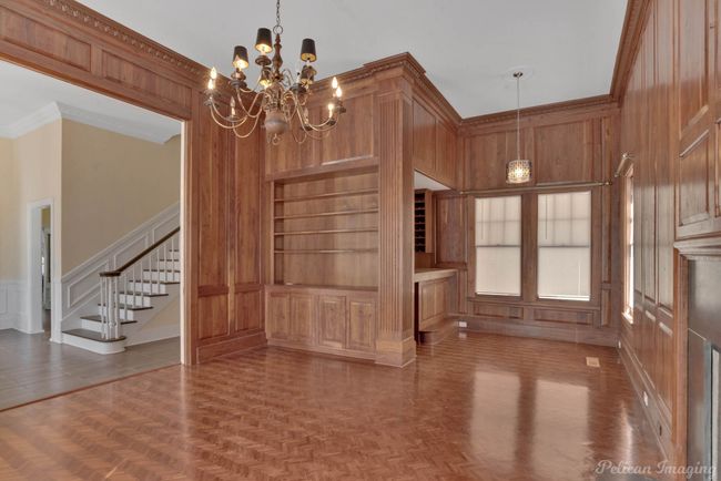 Unfurnished dining area with a decorative wall, a chandelier, stairway, and crown molding | Image 17