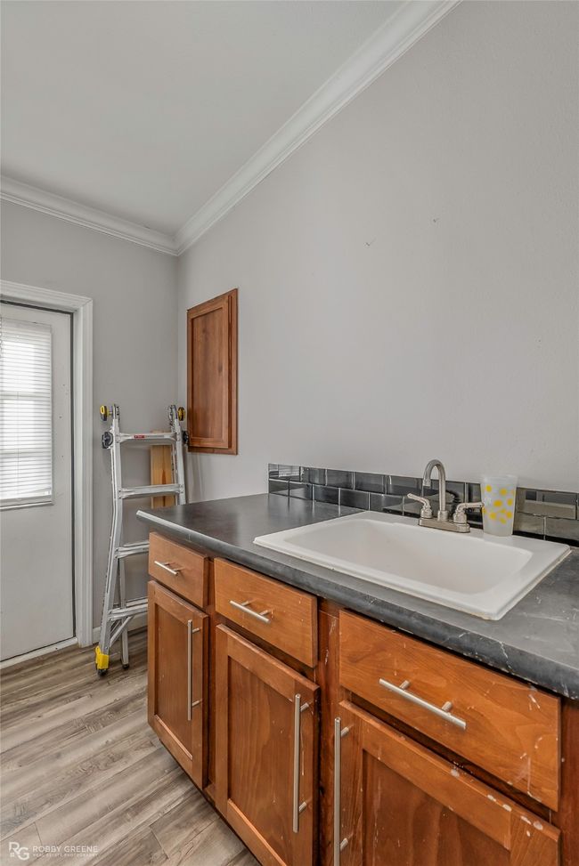 Clothes washing area with crown molding, a sink, and light wood-style flooring | Image 30