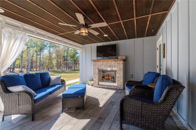 Wooden deck featuring an outdoor living space with a fireplace and ceiling fan | Image 24
