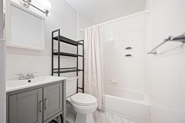 Full bath with tile walls, shower / bath combo, vanity, and toilet | Image 8
