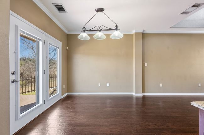 Unfurnished dining area with ornamental molding, wood floors, and lighting. | Image 13