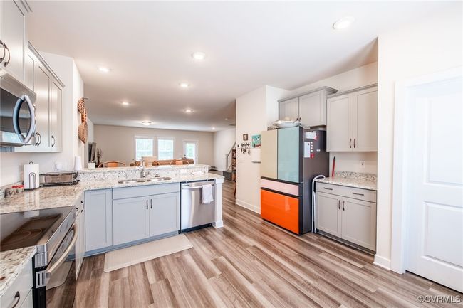 Kitchen featuring appliances with stainless steel finishes, light wood-style floors, gray cabinetry, a peninsula, and recessed lighting | Image 12