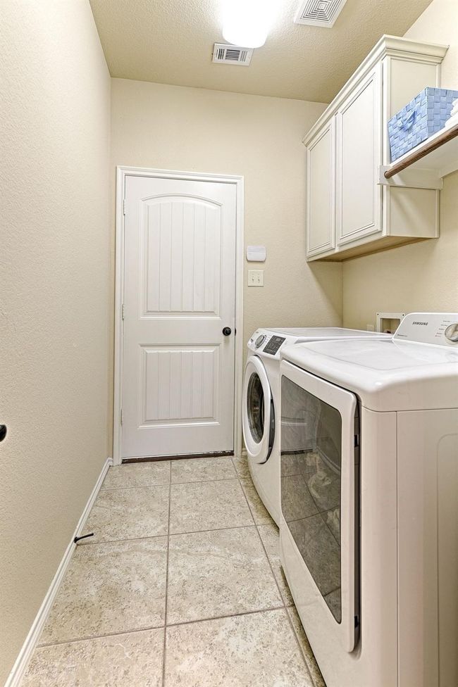 Laundry room with independent washer and dryer, cabinet space, and light tile patterned flooring | Image 20