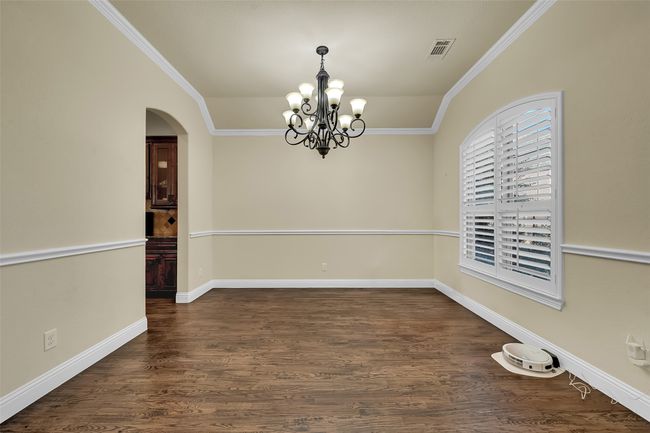 Unfurnished dining area featuring ornamental molding, arched walkways, dark wood-type flooring, and a chandelier | Image 16