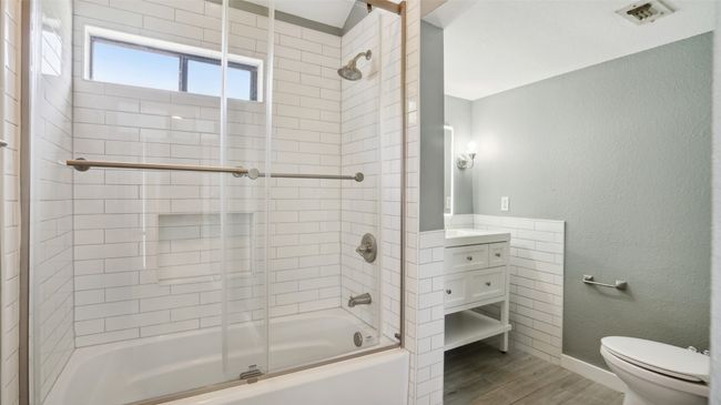 Bathroom featuring toilet, wood finished floors, enclosed tub / shower combo, vanity, and baseboards | Image 21