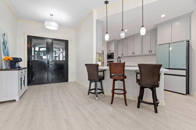 Kitchen featuring stainless steel appliances, gray cabinetry, crown molding, a kitchen bar, and tasteful backsplash | Image 4