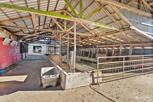 The property features three spacious barns and a former milk house, all connected by holding pens and alleyways for seamless livestock management. An open outdoor arena area adds versatility for training. While the ample covered feeding space ensures convenience and protection for your animals | Image 29
