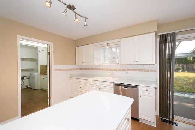 Kitchen featuring stainless steel dishwasher, washer and clothes dryer, healthy amount of natural light, white cabinetry, and tile walls | Image 13