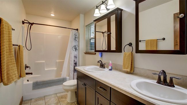 Full bath featuring toilet, shower / bath combination with curtain, double vanity, and tile patterned floors | Image 22