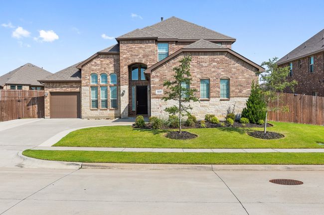 French provincial home featuring brick siding, an attached garage, roof with shingles, and concrete driveway | Image 32