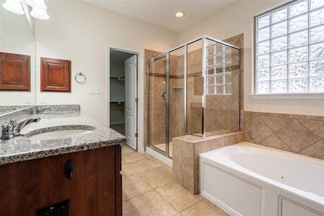 Full bath featuring a stall shower, a bath, double vanity, tile patterned floors, and a walk in closet | Image 17