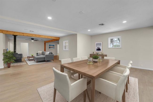 Dining room featuring beam ceiling, a wood stove, light hardwood / wood-style flooring, and ceiling fan | Image 17