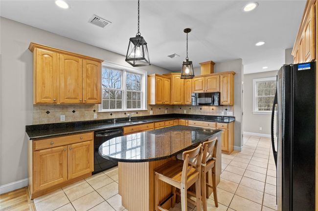 Kitchen with light tile patterned floors, black appliances, a center island, a sink, and decorative backsplash | Image 12
