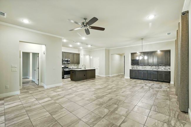 living room with a ceiling fan, ornamental molding, tile flooring | Image 7