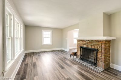 Unfurnished living room featuring wood-type flooring and a brick fireplace | Image 3