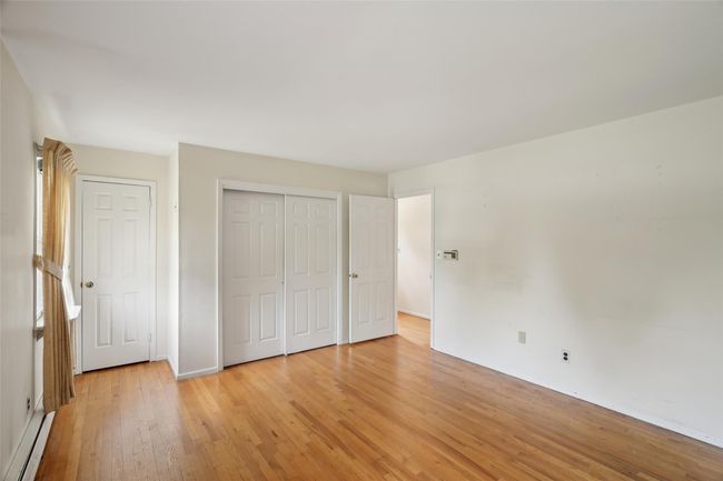 Unfurnished bedroom with light wood finished floors, baseboards, a closet, and a baseboard radiator | Image 21