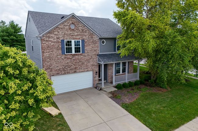 traditional-style house featuring a porch, a shingled roof, brick siding, driveway, and an attached garage | Image 44
