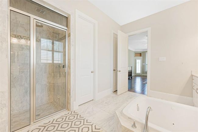Spacious primary bath with dual vanities, jetted soaking tub, and a large walk-in shower with tile surround. | Image 28