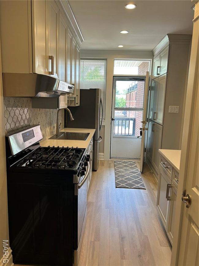 Kitchen featuring range, light countertops, light wood-style flooring, backsplash, and recessed lighting | Image 7