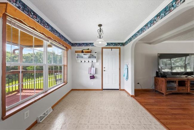 Foyer entrance featuring crown molding, a textured ceiling, baseboards, visible vents, and arched walkways | Image 9