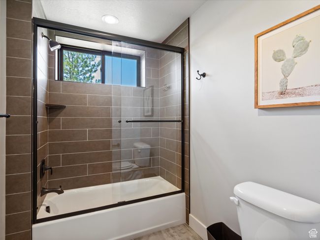 Full bath with toilet, shower / bath combination with glass door, and baseboards | Image 40