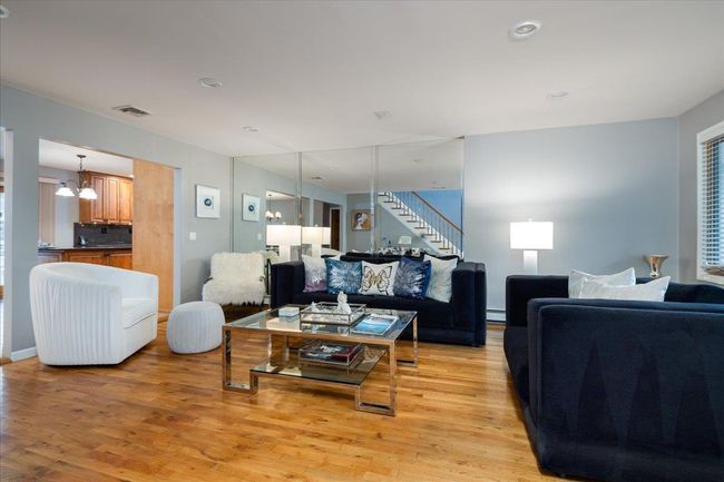 Living room with light wood finished floors, stairway, a chandelier, baseboard heating, and recessed lighting | Image 5