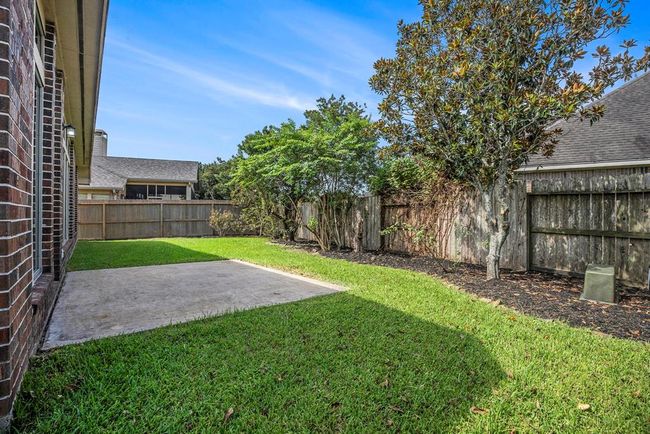 Enjoy a low-maintenance outdoor space with a mix of greenery and shade trees. The private backyard offers a simple concrete patio and a clean landscape—perfect for relaxing or customizing with your own touches. | Image 29