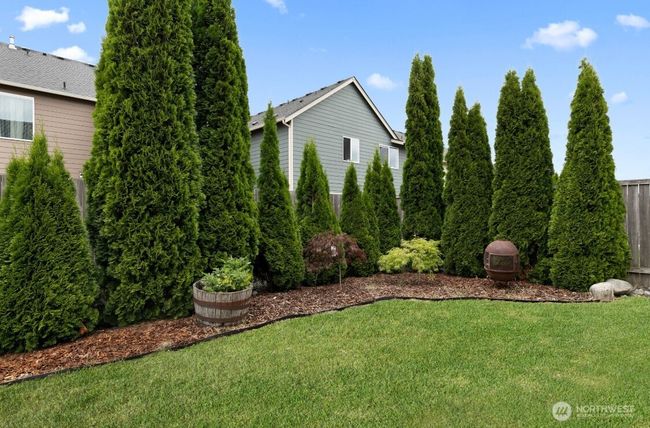 Low-maintenance yard with room to roam and unwind—ideal for enjoying the PNW seasons. Private backyard with mature landscaping and open lawn provides a peaceful retreat right at home. | Image 27