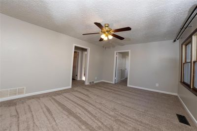 Empty room with ceiling fan, carpet flooring, and a textured ceiling | Image 3