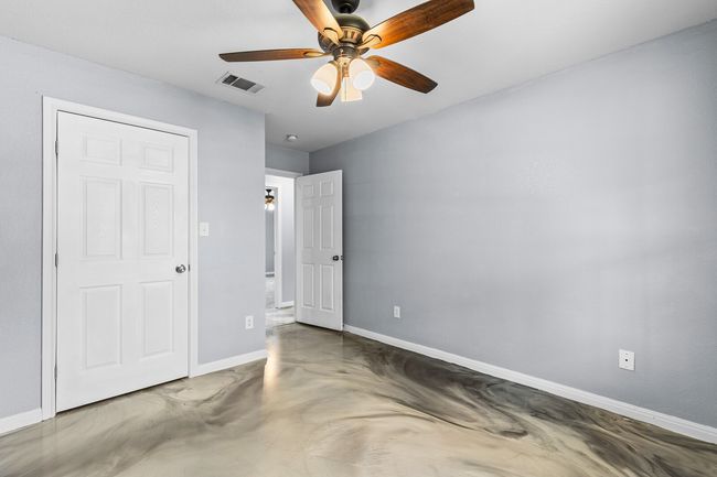 Unfurnished bedroom with concrete floors and ceiling fan | Image 25