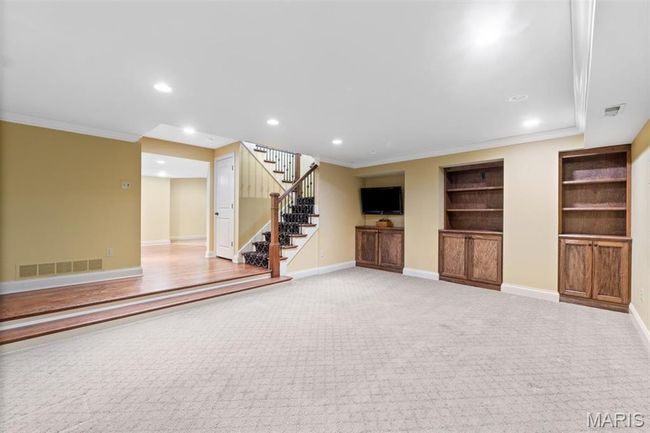 Finished below grade area featuring crown molding, stairs, recessed lighting, carpet flooring, and built in features | Image 45