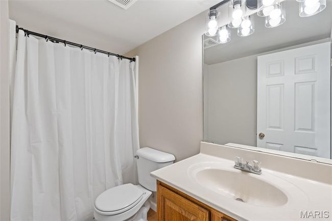 Bathroom with toilet, vanity, and curtained shower | Image 26