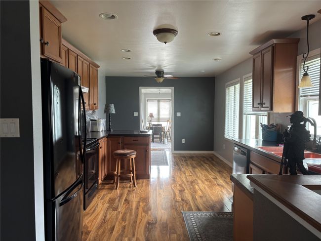 Kitchen featuring black appliances, dark countertops, a peninsula, ceiling fan, and recessed lighting | Image 7