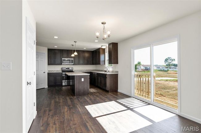 Kitchen with stainless steel appliances, dark brown cabinetry, a chandelier, light countertops, and dark wood-style flooring | Image 12