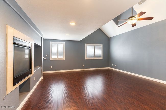Primary bedroom featuring vaulted ceiling, baseboards, visible vents, ceiling fan, and dark wood-style flooring | Image 25