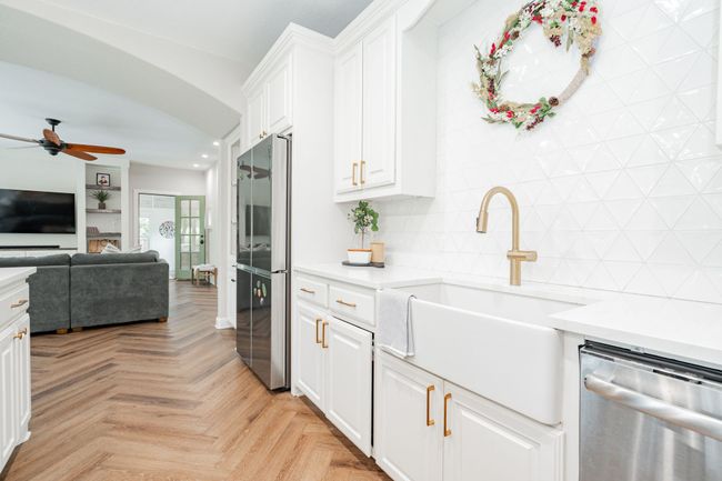 Kitchen featuring open floor plan, light countertops, white cabinetry, a sink, and appliances with stainless steel finishes | Image 8