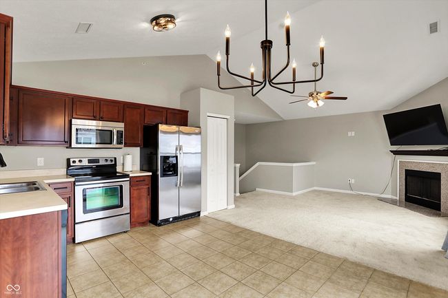 kitchen featuring appliances, tile flooring, open floor plan, light countertops, and a chandelier | Image 14