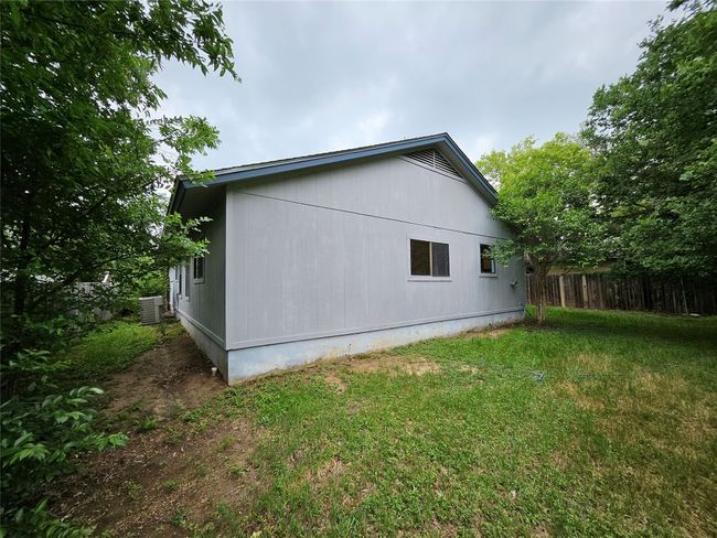 View of property exterior featuring a yard, fence, and central air condition unit | Image 34