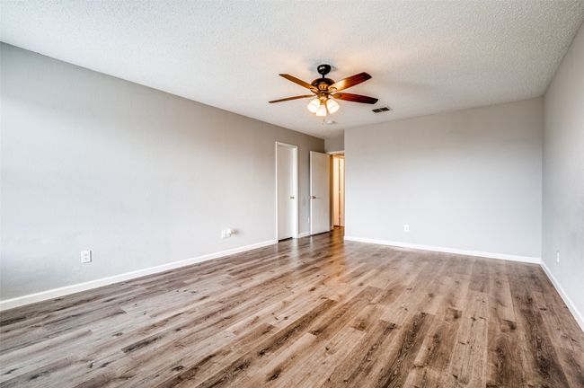 Unfurnished room with ceiling fan, wood finished floors, baseboards, and a textured ceiling | Image 21