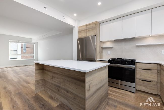Kitchen featuring appliances with stainless steel finishes, modern cabinets, light countertops, light wood finished floors, and recessed lighting | Image 16