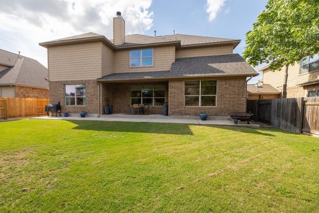 Back of property featuring brick siding, a fenced backyard, a patio area, and a lawn | Image 12