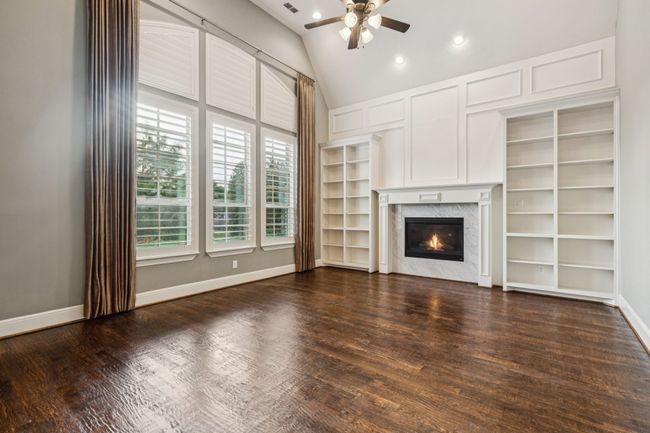 Unfurnished living room featuring ceiling fan, a high end fireplace, dark wood-type flooring, baseboards, and recessed lighting | Image 4